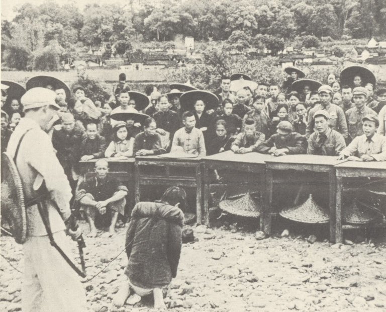 1950 年代初的公审大会:被押者跪在公审台前,全副武装的民兵在旁看守(美国国家档案馆藏)。