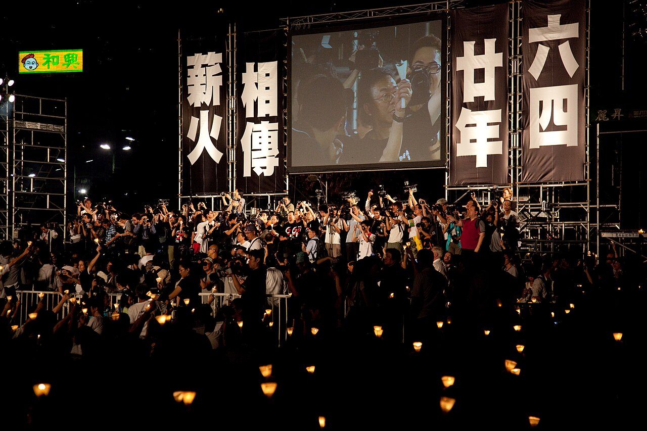 2009 年 6 月 4 日,香港维多利亚公园,约十五万人出席六四二十周年烛光悼念晚会,巨幅标语写着「薪火相传」。彼时,
