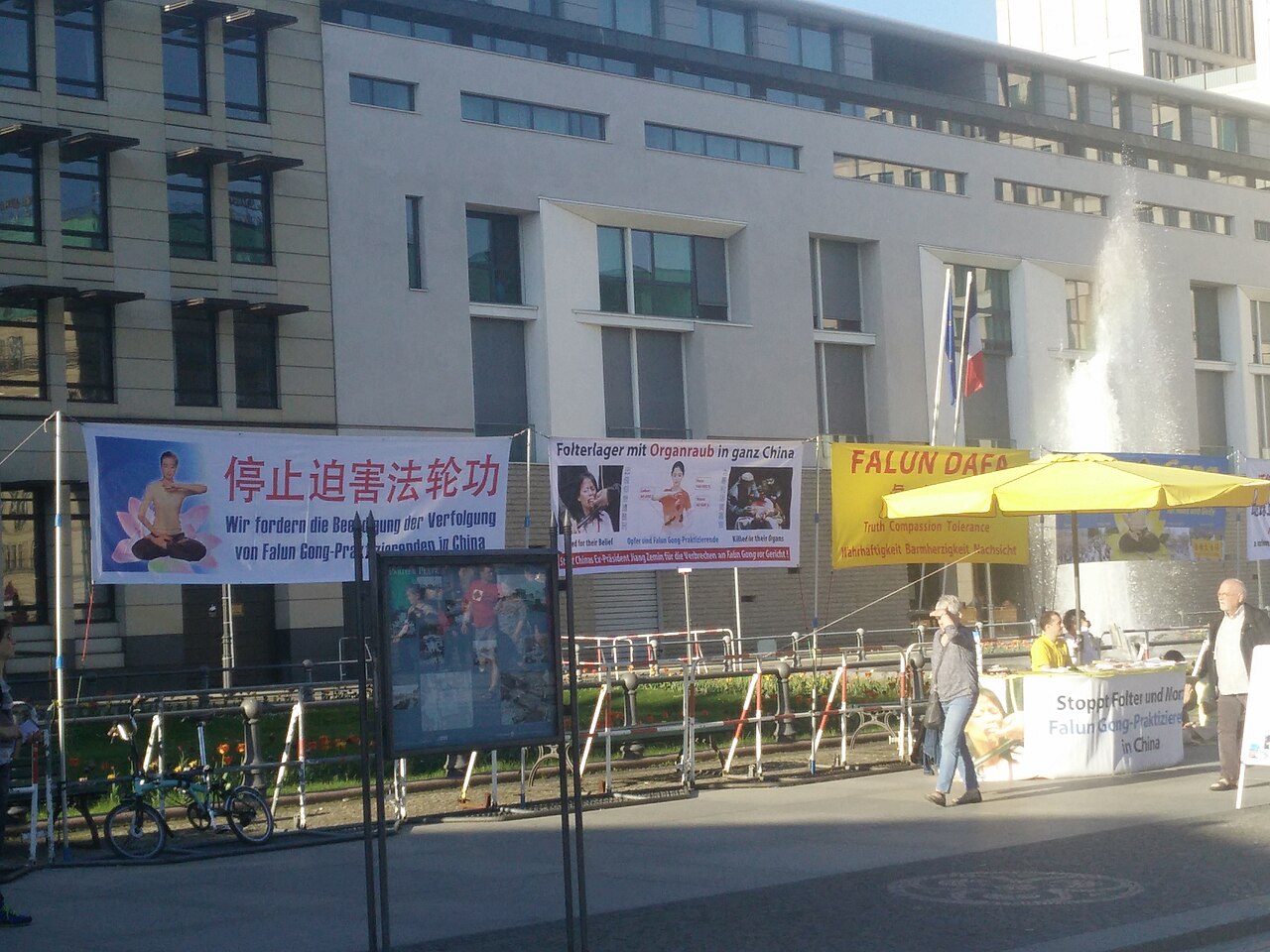 2018 年,柏林勃兰登堡门前:法轮功学员以中德双语横幅抗议——「停止迫害法轮功」「遍布中国的劳教所与器官掠夺」。